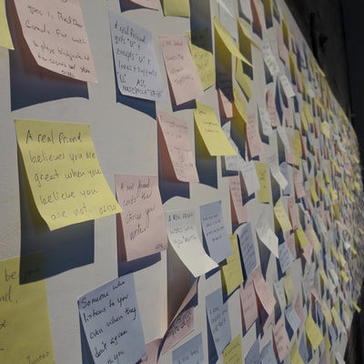 A photograph of the post-it notes left by visitors to the Tanja Hollander exhibit at MASS MoCA. Each post-it gives a perspective on what it means to be a real friend.